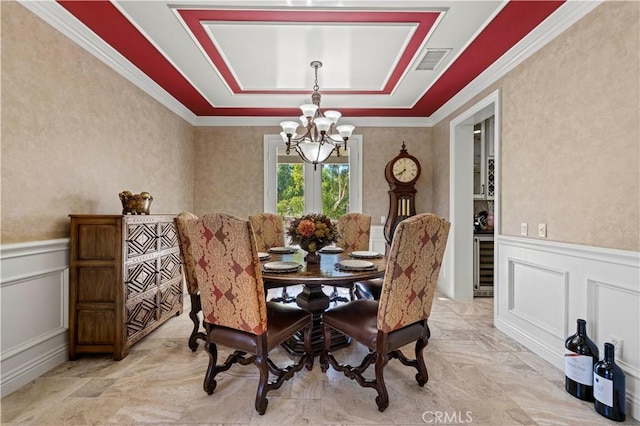 dining space featuring a tray ceiling, wine cooler, a chandelier, and ornamental molding