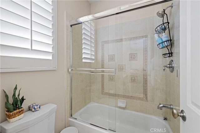 bathroom featuring toilet and combined bath / shower with glass door