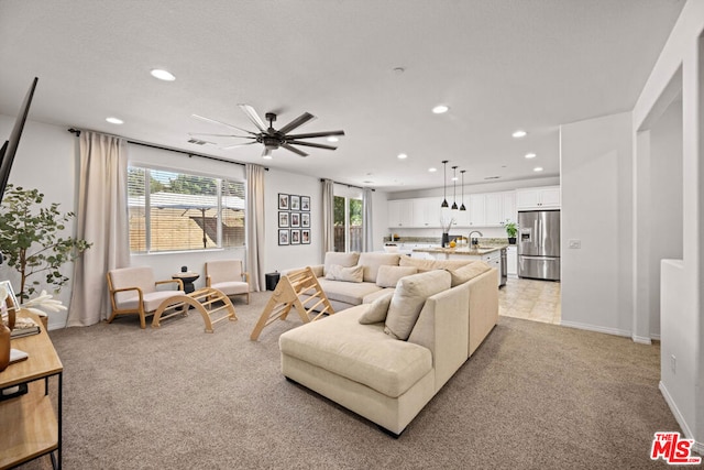 living room with ceiling fan, sink, and light carpet