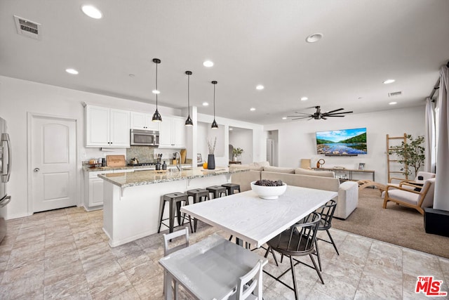 dining space featuring ceiling fan and sink