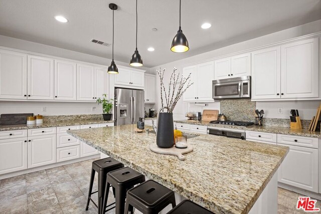 kitchen featuring white cabinets, stainless steel appliances, a kitchen island, and hanging light fixtures