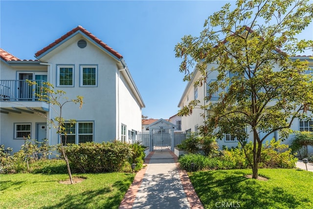 view of front of house with a balcony and a front lawn