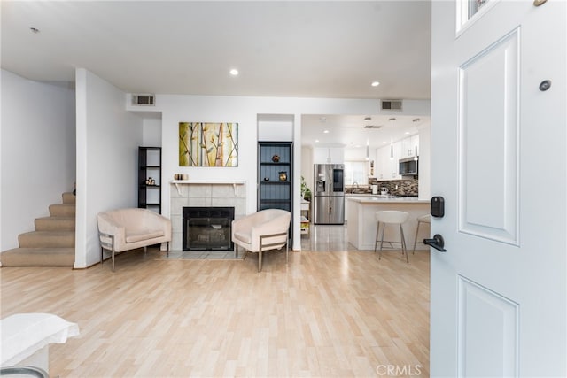 living room featuring light hardwood / wood-style floors and a tiled fireplace