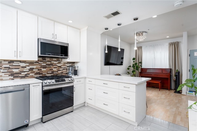 kitchen featuring decorative light fixtures, stainless steel appliances, kitchen peninsula, and white cabinetry