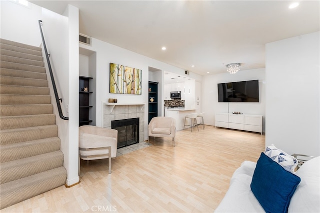 living room featuring light hardwood / wood-style flooring and a tiled fireplace