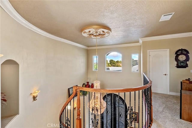 corridor featuring ornamental molding, carpet floors, and a textured ceiling