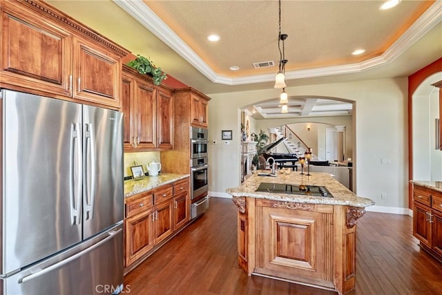 kitchen with stainless steel appliances, hanging light fixtures, a center island, and a tray ceiling