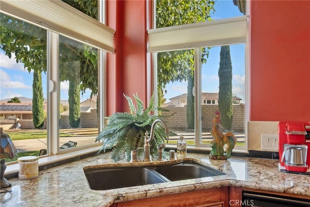 interior details featuring light stone counters, black dishwasher, and sink