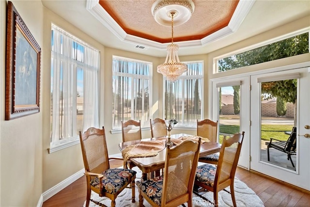 sunroom / solarium with a raised ceiling and a chandelier