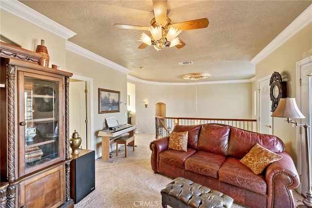 carpeted living room with ceiling fan, ornamental molding, and a textured ceiling