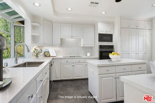 kitchen with black appliances, a center island, white cabinetry, decorative backsplash, and sink