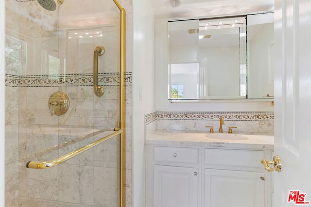 bathroom with a shower with shower door and vanity