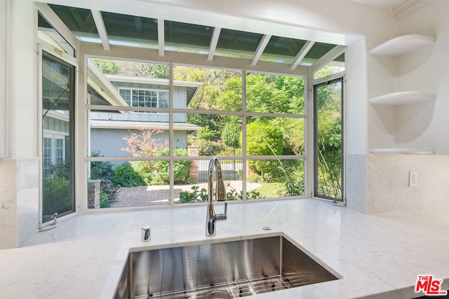 kitchen featuring decorative backsplash, sink, and light stone counters