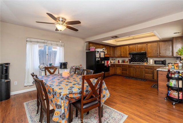 dining space with ceiling fan and dark wood-type flooring