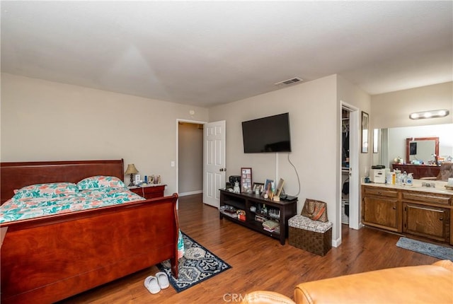 bedroom featuring a closet, wood finished floors, visible vents, and ensuite bathroom