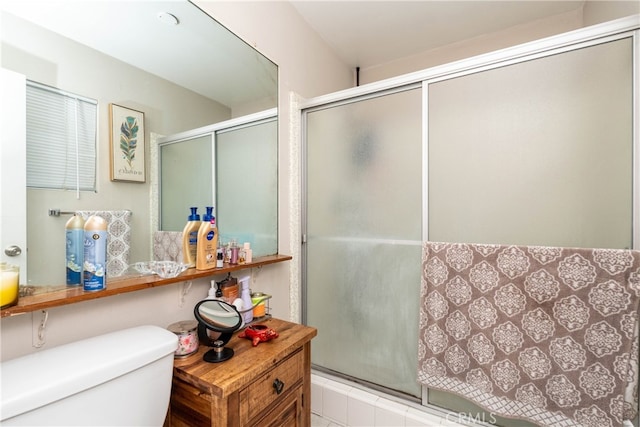 bathroom featuring a shower with door and toilet