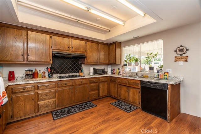 kitchen with black appliances, a raised ceiling, hardwood / wood-style floors, and sink