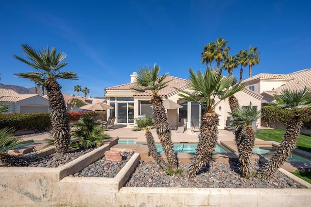 back of house with a patio area and a pool with hot tub