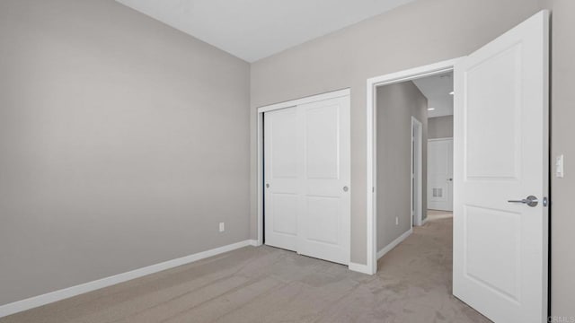 unfurnished bedroom featuring a closet and light colored carpet