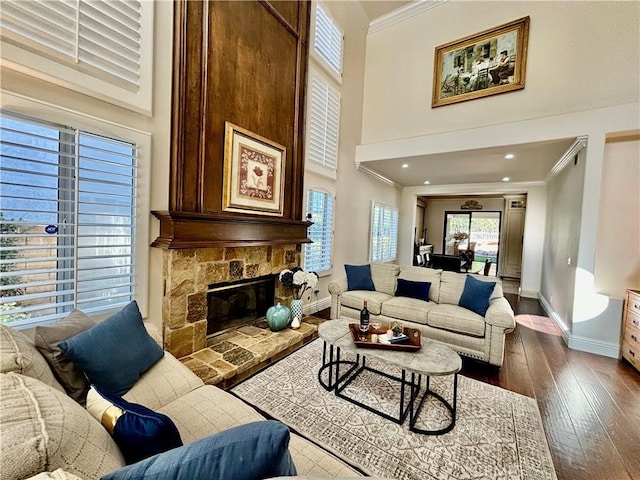 living room with a fireplace, ornamental molding, dark wood-type flooring, and a high ceiling