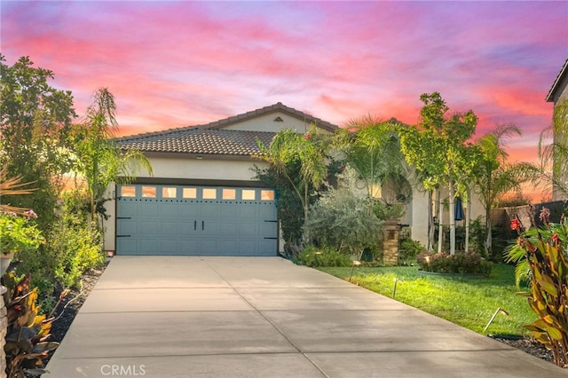 mediterranean / spanish-style home featuring a garage and a lawn