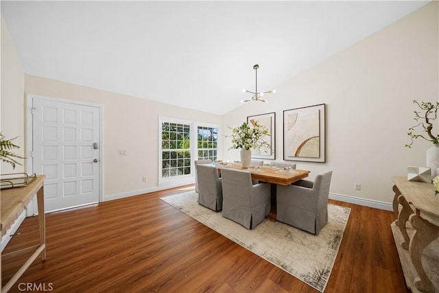 dining area featuring dark wood-type flooring, vaulted ceiling, and a notable chandelier