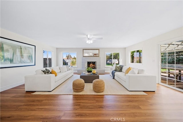 living room with ceiling fan, light wood-type flooring, and a tile fireplace