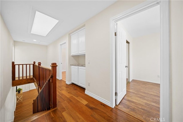 hallway featuring a skylight and light hardwood / wood-style flooring