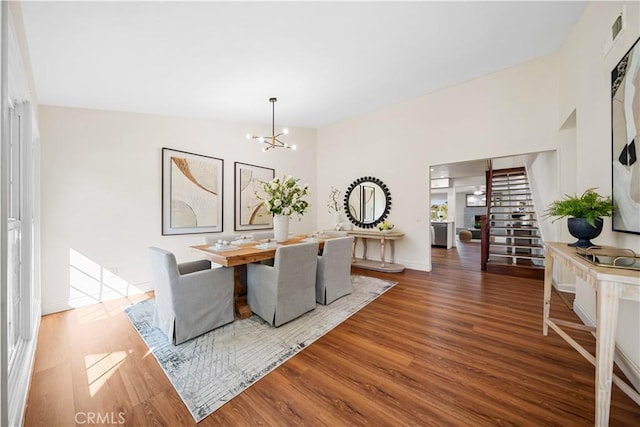 dining area with a notable chandelier, vaulted ceiling, and hardwood / wood-style flooring