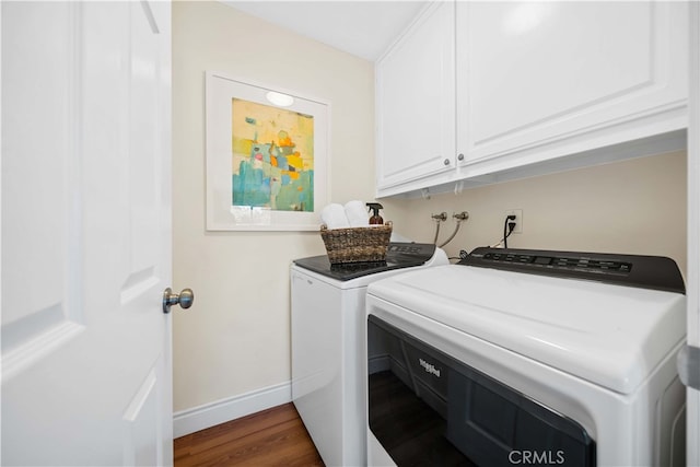 clothes washing area with washer and dryer, cabinets, and dark wood-type flooring