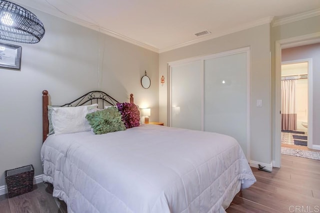 bedroom featuring wood-type flooring, ensuite bathroom, a closet, and crown molding