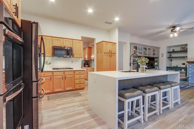 kitchen with a kitchen island with sink, light hardwood / wood-style flooring, stainless steel appliances, and sink