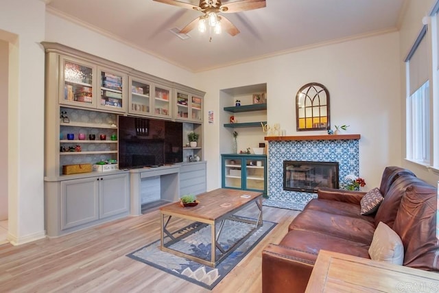 living room with a fireplace, crown molding, light hardwood / wood-style flooring, and built in features