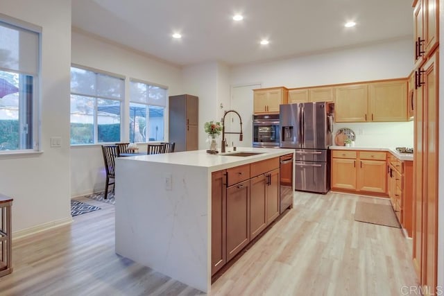 kitchen featuring a center island with sink, crown molding, sink, light hardwood / wood-style flooring, and stainless steel appliances