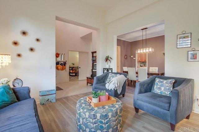 living room with a towering ceiling, light hardwood / wood-style flooring, and a notable chandelier