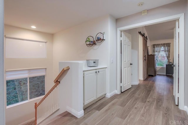 hallway featuring a barn door and light hardwood / wood-style flooring