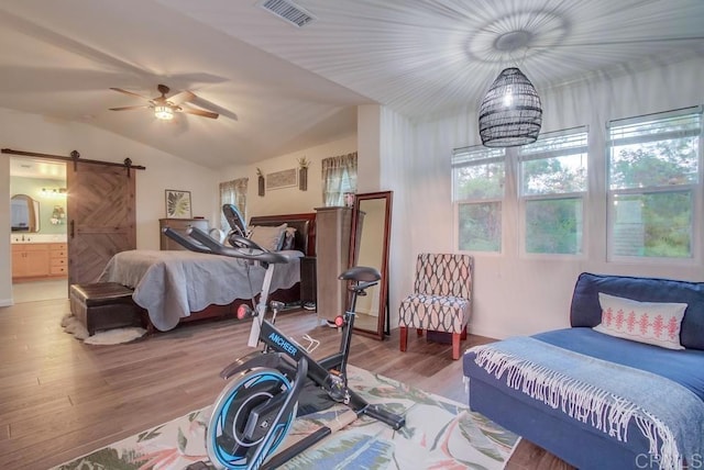 bedroom featuring hardwood / wood-style flooring, ceiling fan with notable chandelier, a barn door, and vaulted ceiling