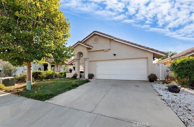 view of front of property with an attached garage, a tiled roof, concrete driveway, and stucco siding