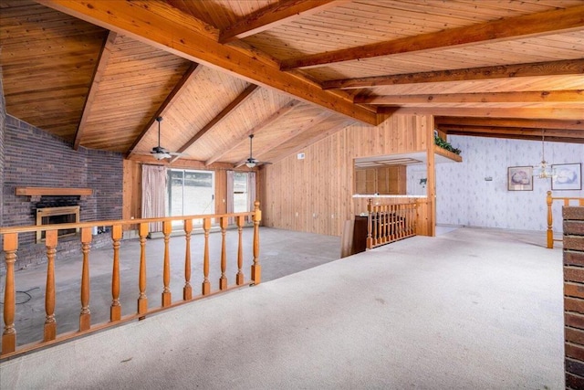 interior space featuring carpet, ceiling fan, wooden ceiling, a fireplace, and vaulted ceiling with beams