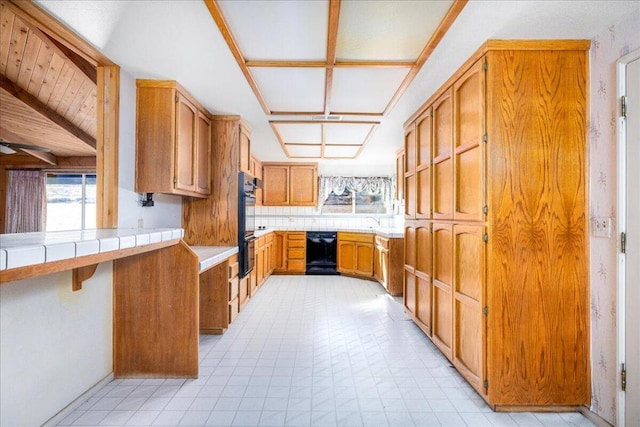 kitchen with tile countertops, kitchen peninsula, vaulted ceiling, decorative backsplash, and black appliances