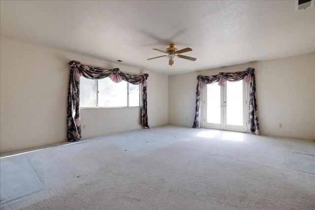 unfurnished room with ceiling fan, a textured ceiling, light carpet, and french doors