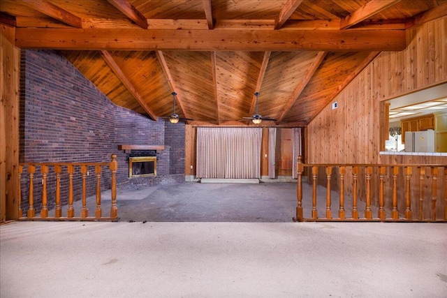 unfurnished living room featuring a brick fireplace, brick wall, ceiling fan, wooden ceiling, and vaulted ceiling with beams