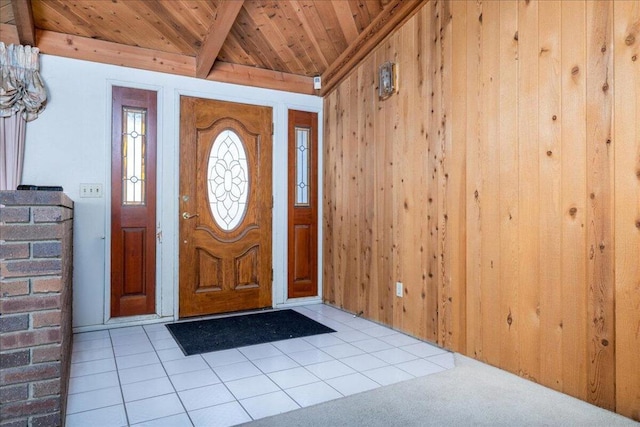 foyer entrance with vaulted ceiling with beams, light tile patterned flooring, wooden ceiling, and wooden walls