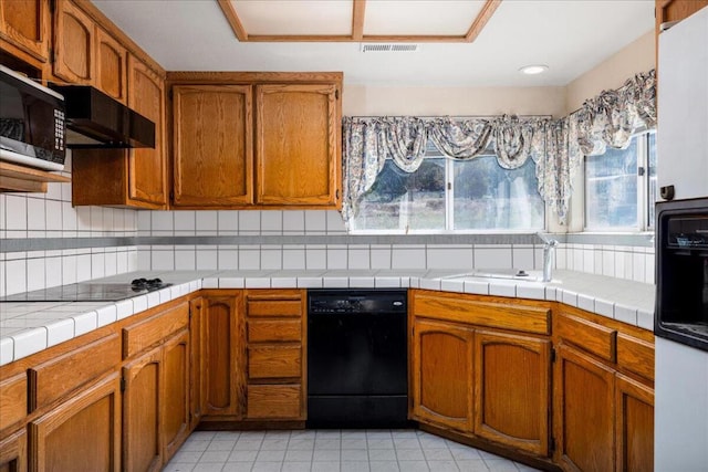 kitchen featuring black appliances, decorative backsplash, a healthy amount of sunlight, and tile counters