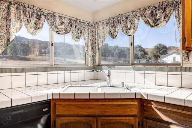 interior space featuring dishwasher, tile counters, sink, a mountain view, and decorative backsplash