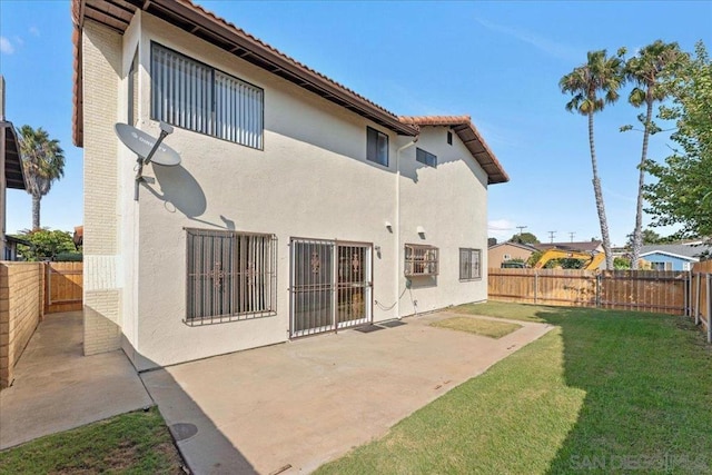 back of house with a patio area and a lawn