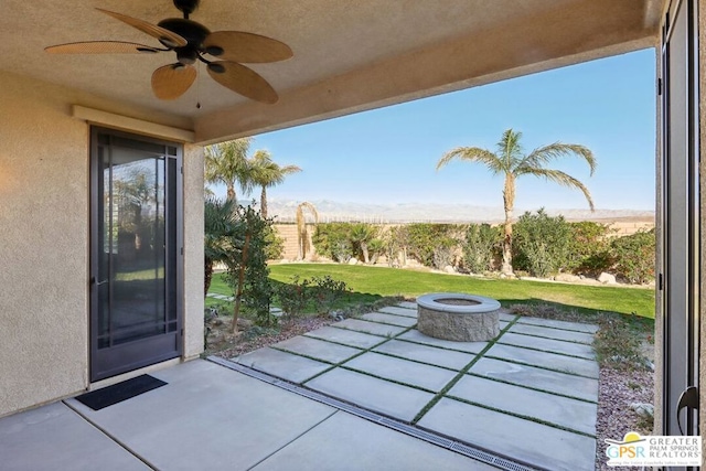 view of patio with ceiling fan and an outdoor fire pit