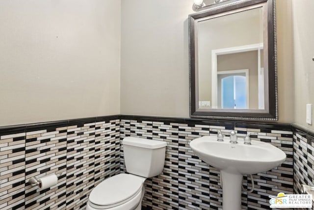 bathroom with tile walls and toilet