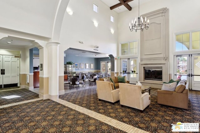 living room featuring ornate columns, a high ceiling, a notable chandelier, and french doors