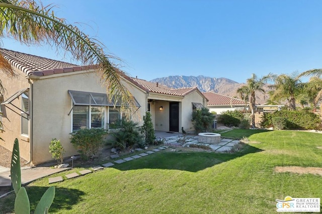 view of front of property with a mountain view, a fire pit, and a front yard